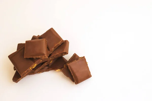 Fatias de chocolate são empilhadas em um fundo branco.Chocolate escuro com nozes . — Fotografia de Stock