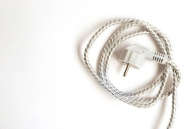 Elektrik prizi beyaz. Örgülü kordon daire şeklinde yuvarlandı. Elektrik akımı. Teknolojiler.