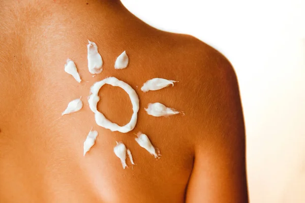 Cream painted the sun on the back of the child. Tanned skin. Sunscreen.
