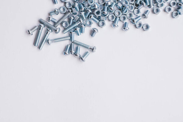 Вид сверху хромированных винтовых гаек и болтов. Болты и гайки на белом фоне. Строительная промышленность. Ремонт
.