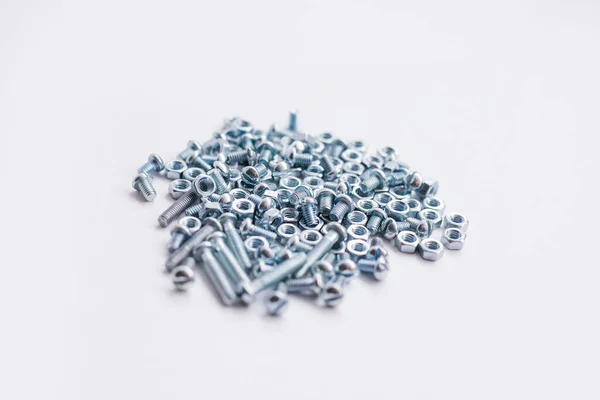 Chrome-plated screw nuts and bolts top view. Bolts and nuts on a white background. Construction industry. — Stock Photo, Image