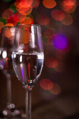 Noel ışıklarının arka planında şampanya bardakları. Arka planda Noel çelengi.