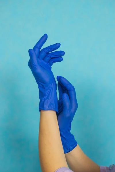 Mavi tıbbi eldivenlerde kadın eli. Doktor ya da hemşire mavi nitril cerrahi eldivenler, profesyonel tıbbi güvenlik ve hijyen ve mavi arka planda tıbbi muayene giyer..