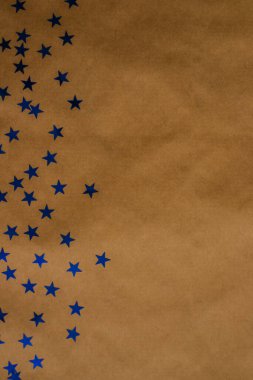 Bayram pulları Kraft kağıdına saçılmış. Yeni yıl arkaplanı. Mavi yıldız şeklinde tohumlar..