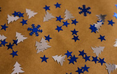 Yeni yılın konfeti geçmişi mavidir. Kraft kağıdının üzerinde çeşitli şekiller bulunur. Şenlik arka planı. Kağıdın dokusu..