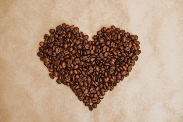 Heart made of coffee beans. Roasted coffee beans on Kraft paper.
