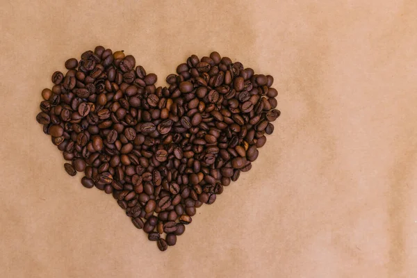 Heart made of coffee beans. Roasted coffee beans on Kraft paper.