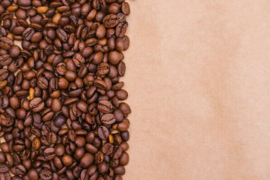 Kahve fasülyesi geçmişi. Koyu kavrulmuş kahve çekirdekleri Kraft kağıdına saçılmış. Doku.