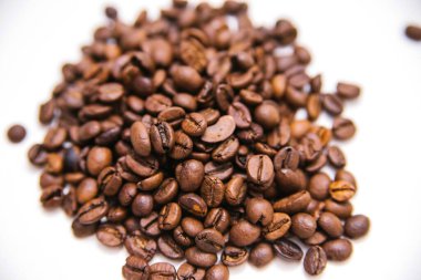 Kahve çekirdekleri beyaz arka plana saçılmış..