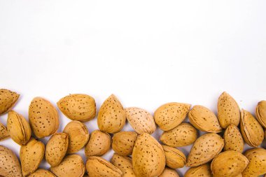 Beyaz arka planda kabuklu badem. Bademler yığın halinde dizilir..