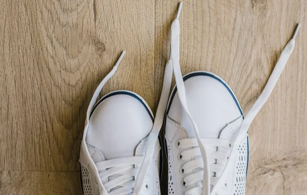White sneakers with untied laces. Casual shoes. Shoes for sports.