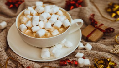 Örgü kumaşlı arkaplanlı marşmelovlu kahve, hediyeler ve tatil kaseleri. Sıcak kış içeceği. Kakao ve kapuçino. Şenlik, yeni yıl arkaplanı..