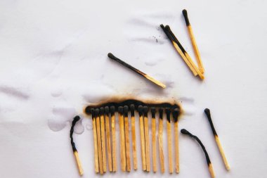 Kibritler beyaz arka planda sıralanmış siyah kibritler var. Yangın suyla söndürülmüş..