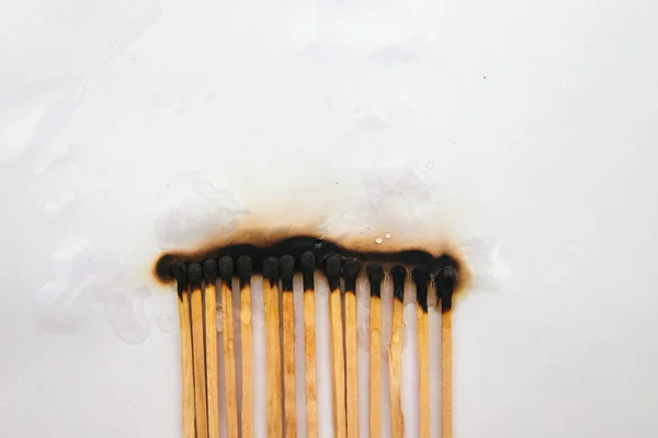 Matches stand in a row on a white background..There are black burnt matches.The fire was extinguished with water.