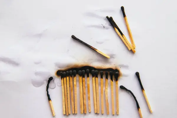 Matches stand in a row on a white background..There are black burnt matches.The fire was extinguished with water.