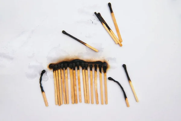 Matches stand in a row on a white background..There are black burnt matches.The fire was extinguished with water.