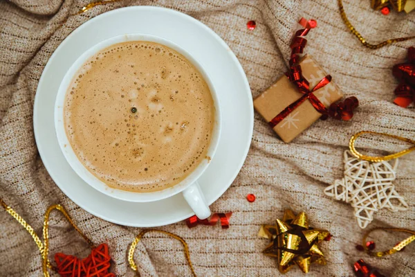 Kaffee auf einem Hintergrund aus Strickstoff mit Geschenken und Feiertagsschalen. Heißes Wintergetränk. Kakao und Cappuccino. — Stockfoto