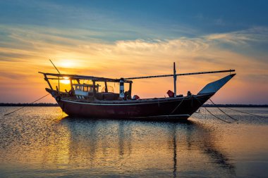 Dammam 'da tek bir tekne, arka plan gündoğumu manzaralı. Dammam, Suudi Arabistan.