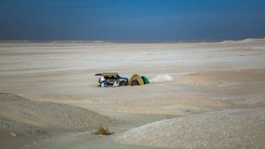 Küçük bir grup insan arabasının yakınındaki çölde, Dhahran, Suudi Arabistan yakınlarındaki bir çadırda dinleniyorlar..