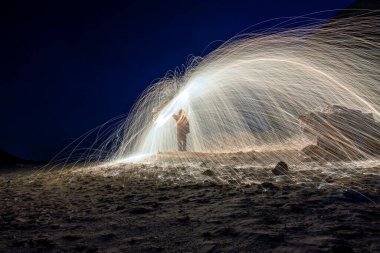 Geceleri yanan bir çelik yün (yavaş bir deklanşör hızı ile gece fotoğrafçılığı) - konu üzerine odaklanmış bir galaksi arka planı.