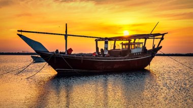 Dammam 'da tek bir tekne, arka plan gündoğumu manzaralı. Dammam, Suudi Arabistan.