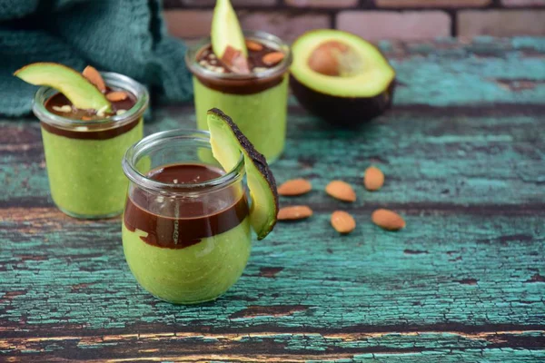 Avocado chocolate pudding with chopped almonds on wooden background