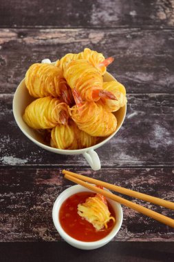 Patates İpli Karidesler. Asya usulü yemekler, patates ipine sarılı kral karidesler ve acı biber sosuyla servis edilen kızarmış patates.