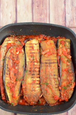 Grilled eggplants with tomato onion sauce as background