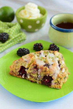 Krem şantili ve bir fincan kahveyle servis edilen jöleli şeker ve limonlu böğürtlenli çörekler.