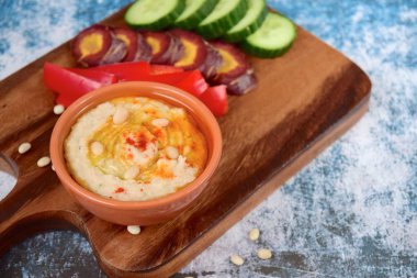 Kırmızı biber çubuklu beyaz fasulye humusu, dilimlenmiş salatalık ve mor havuç.