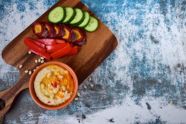 Kırmızı biber çubuklu beyaz fasulye humusu, dilimlenmiş salatalık ve mor havuç.