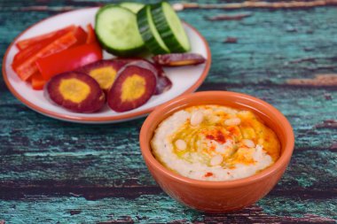 Kırmızı biber çubuklu beyaz fasulye humusu, dilimlenmiş salatalık ve mor havuç.