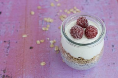 Kahvaltı chia pudingi, yulaf, yoğurt ve ahududu ve pembe arka planda