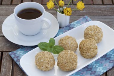 Susam tohumu topları ya da Onde-onde. Endonezya geleneksel sokak yemekleri. glutinous pirinç unu susam tohumlarıyla kaplı mung fasulyesi ezmesi ile doldurulmuş. Bir fincan kahveyle servis edilir.