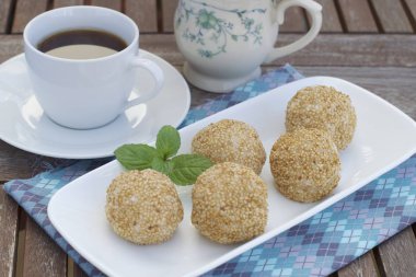 Susam tohumu topları ya da Onde-onde. Endonezya geleneksel sokak yemekleri. glutinous pirinç unu susam tohumlarıyla kaplı mung fasulyesi ezmesi ile doldurulmuş. Bir fincan kahveyle servis edilir.