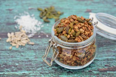 Glütensiz yulaf, kabak çekirdeği, ayçekirdeği, Hindistan cevizi taneleri, akçaağaç şurubu ve hindistan cevizi yağından yapılmış ev yapımı granola. Yeşil tahta arkaplan