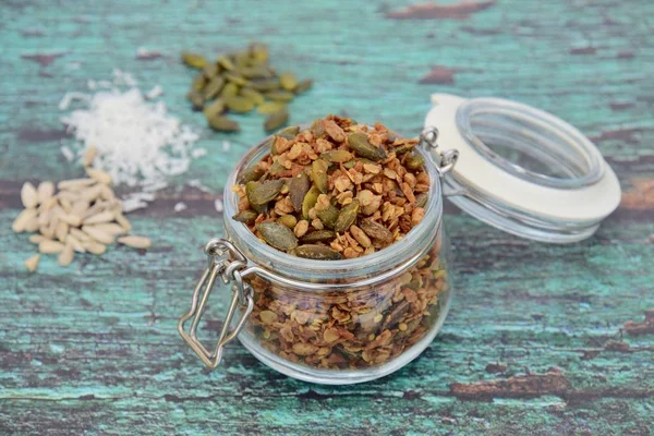 Glütensiz yulaf, kabak çekirdeği, ayçekirdeği, Hindistan cevizi taneleri, akçaağaç şurubu ve hindistan cevizi yağından yapılmış ev yapımı granola. Yeşil tahta arkaplan