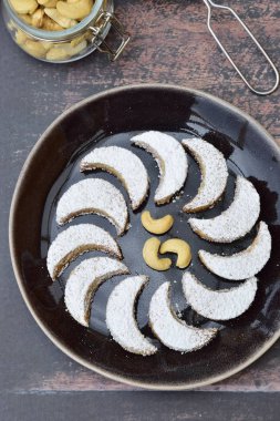 Putri Salju Kacang Mede ya da pudra şekerli kaju fıstığı kaplı hilal şeklinde kurabiyeler. Bayram ya da Idul Fitri 'yi kutlamak için Endonezya' nın popüler tatlıları. Koyu kahverengi arkaplan