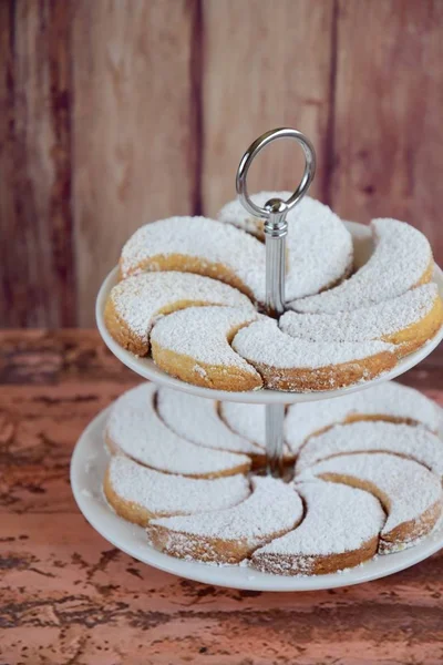Putri Salju or crescent-shaped cookies coated with powdered sugar, arrange on cake stand. Traditional Indonesian cookies to celebrate Eid al Fitr, Festival of Breaking the Fast.