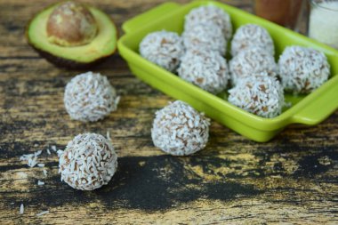 Ev yapımı çiğ avokado çikolatalı trüf, fındık, tohum ve ahşap arka planda hindistan cevizi taneleri.