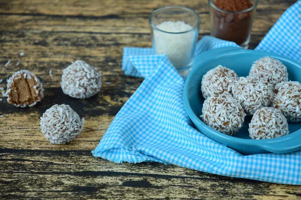 Homemade raw avocado chocolate truffles with nuts, seeds and coconut flakes on wooden background