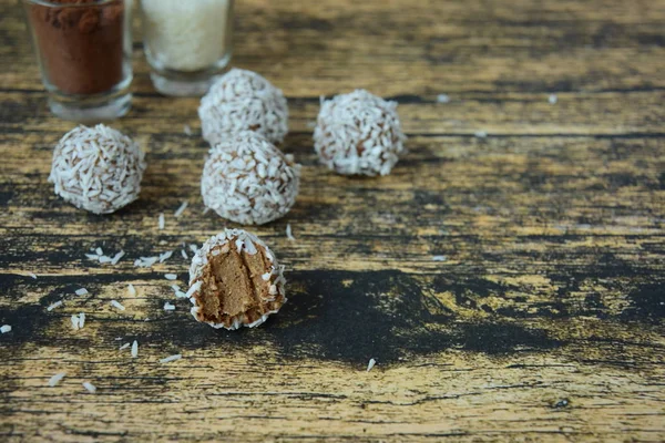 Homemade raw avocado chocolate truffles with nuts, seeds and coconut flakes on wooden background