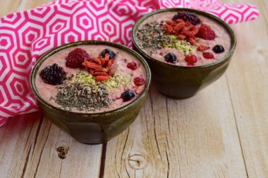 Meyve, kenevir tohumu, chia tohumu ve kakao parçacıkları ile meyve suyu kaseleri.