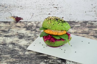 Nohut köftesi, tahin, ıspanak, kırmızı lahana ve susam tohumlu vegan avokado burgeri.