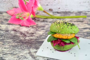 Kırmızı lahana, ıspanak, nohut karnabaharı ve susam tohumlu tahin serpiştirilmiş sağlıklı vegan avokado burgeri..