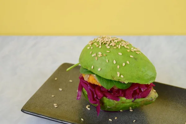 Vegan avocado burger with chickpea patty, tahini, spinach, red cabbage and sesame seeds