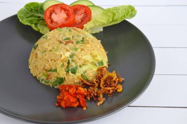 Nasi Goreng, Endonezya usulü yumurta ve soğanlı pilav. Sambal, kızarmış arpacık soğanı, taze salatalık dilimleri, domates ve marul ile servis edilir.