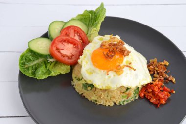 Nasi Goreng, Endonezya usulü kızarmış pilav, yanında yumurta, salatalık dilimleri, domates ve salatayla süslenmiş.