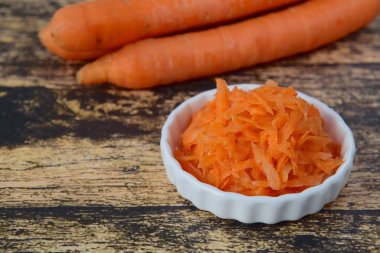 Ahşap zeminde taze organik rendelenmiş havuç.