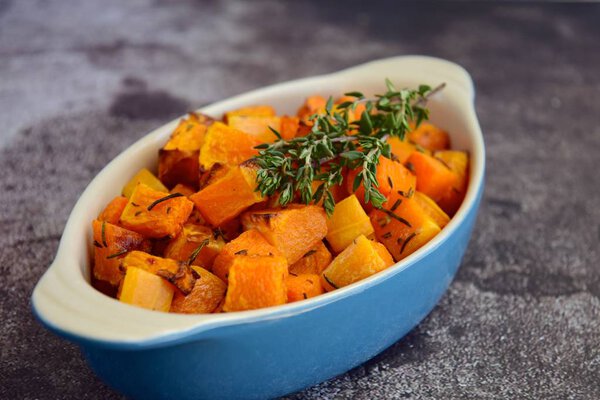 Roasted cubed butternut squash with thyme on grey background. Top view